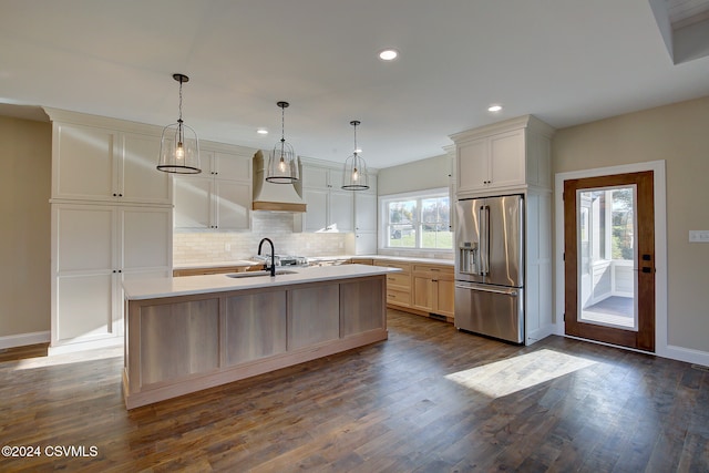 kitchen with dark hardwood / wood-style floors, an island with sink, high quality fridge, and hanging light fixtures