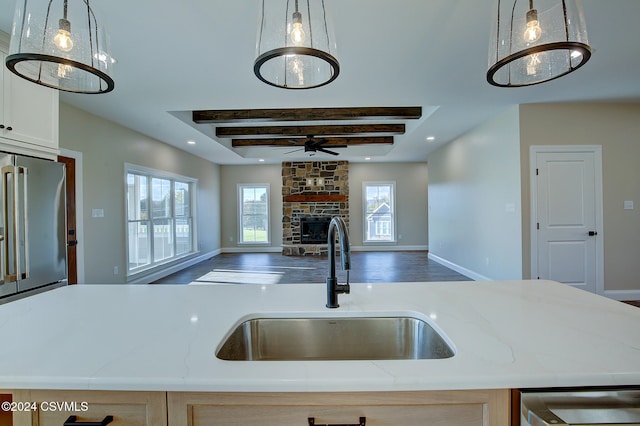 kitchen with a center island with sink, high quality fridge, a fireplace, and pendant lighting