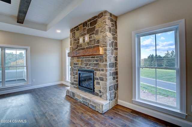 unfurnished living room featuring hardwood / wood-style floors, beam ceiling, and a fireplace