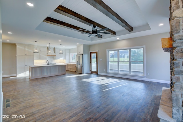 unfurnished living room with dark wood-type flooring, ceiling fan, beam ceiling, and sink