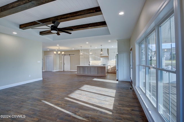 unfurnished living room with sink, beamed ceiling, dark wood-type flooring, and ceiling fan with notable chandelier