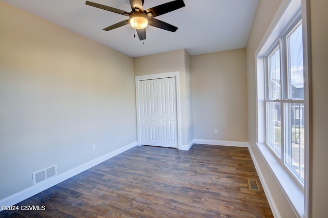 unfurnished bedroom with a closet, ceiling fan, and dark hardwood / wood-style flooring