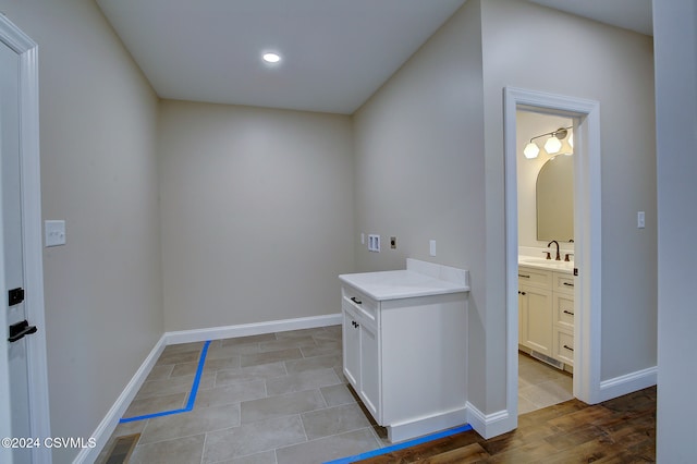 clothes washing area with hookup for an electric dryer, sink, light hardwood / wood-style flooring, and washer hookup