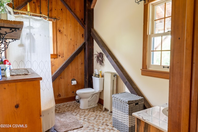 bathroom featuring radiator heating unit, vanity, toilet, and wooden walls