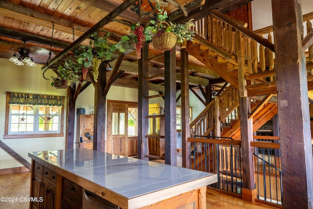 kitchen with beam ceiling, a kitchen island, wood ceiling, and light hardwood / wood-style flooring