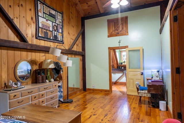 interior space featuring wood ceiling, wooden walls, lofted ceiling with beams, and light wood-type flooring