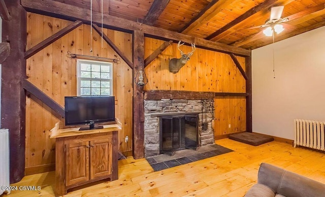 living room with beam ceiling, light hardwood / wood-style flooring, wooden ceiling, radiator heating unit, and a stone fireplace