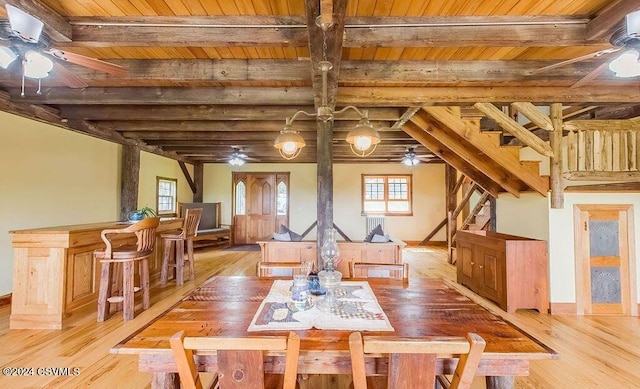 dining room with beamed ceiling, wood ceiling, and light hardwood / wood-style floors