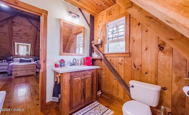 bathroom featuring vanity, wood walls, wood-type flooring, toilet, and wood ceiling