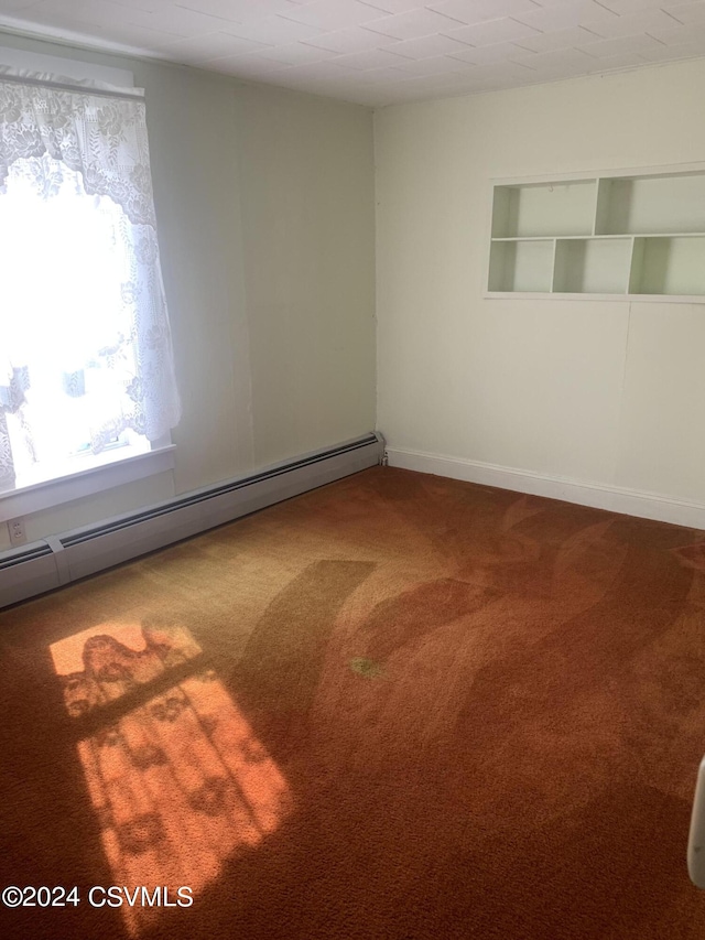 carpeted empty room with built in shelves and baseboard heating