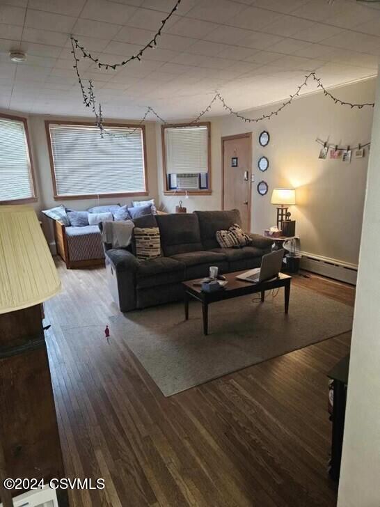 living room featuring cooling unit, a baseboard radiator, and wood finished floors