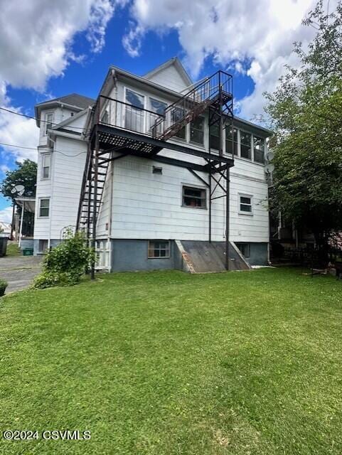 back of house with stairway, a balcony, and a lawn