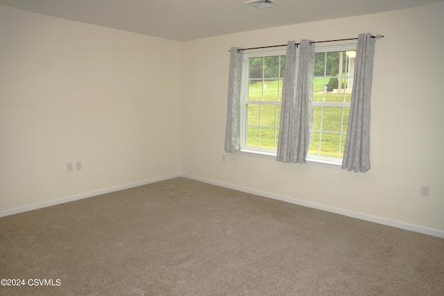 spare room with carpet floors, visible vents, and baseboards