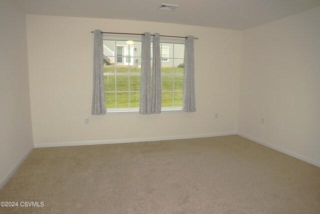 carpeted empty room featuring visible vents and baseboards