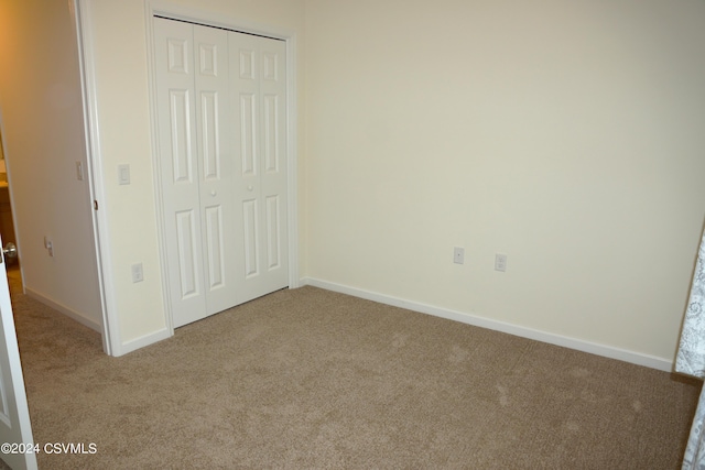 unfurnished bedroom with a closet, carpet, and baseboards