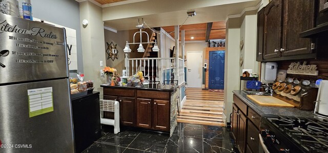 kitchen featuring dark brown cabinets, dark tile flooring, stainless steel fridge, and stove