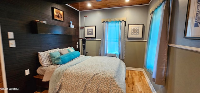 bedroom featuring light hardwood / wood-style flooring, wood ceiling, and crown molding