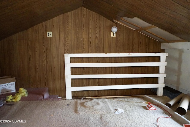 additional living space with wooden walls, carpet floors, and lofted ceiling