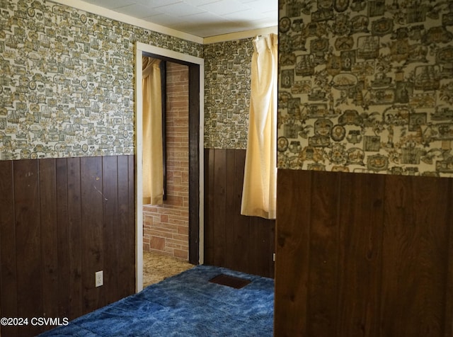 hallway with carpet flooring and wooden walls