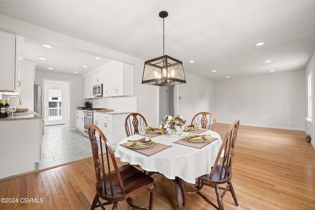 dining space featuring a chandelier, sink, and light hardwood / wood-style floors