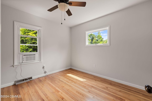 spare room featuring a wealth of natural light, light wood-type flooring, cooling unit, and ceiling fan