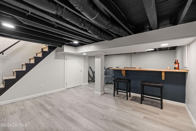 basement featuring indoor bar and light hardwood / wood-style flooring