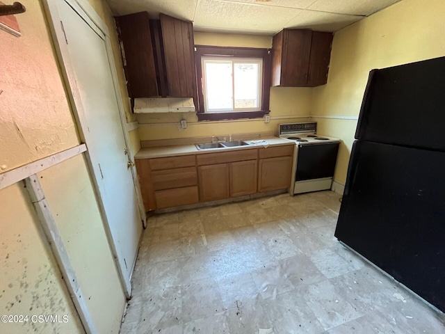 kitchen with a drop ceiling, a sink, electric stove, light countertops, and freestanding refrigerator