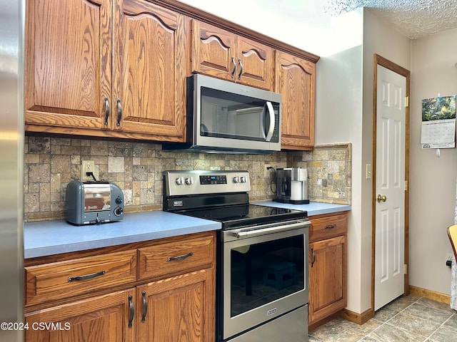 kitchen with decorative backsplash, appliances with stainless steel finishes, and light tile patterned floors