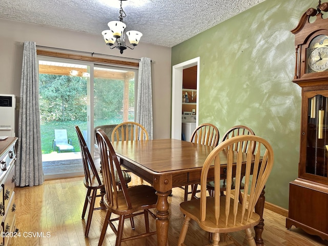 dining area with washer / clothes dryer, a healthy amount of sunlight, light wood-type flooring, and an inviting chandelier