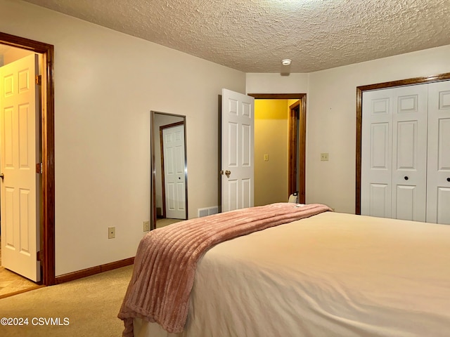 carpeted bedroom with a closet and a textured ceiling