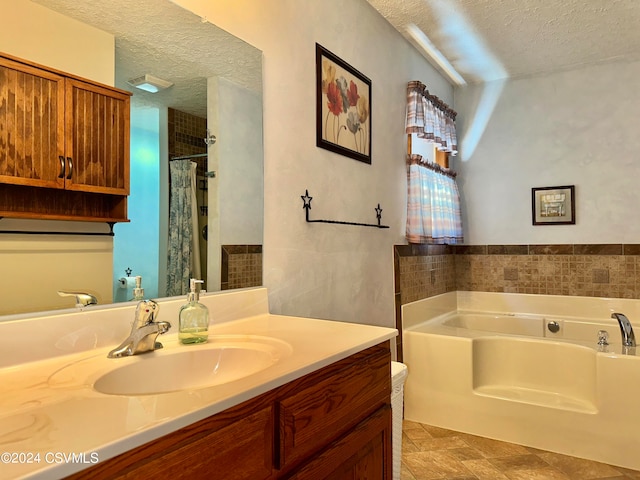 bathroom featuring vanity, a washtub, a textured ceiling, and tile patterned flooring