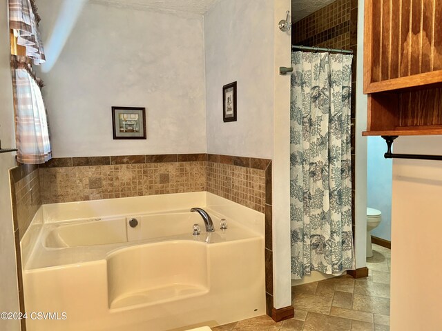 bathroom with tile patterned floors, a textured ceiling, toilet, and a bath