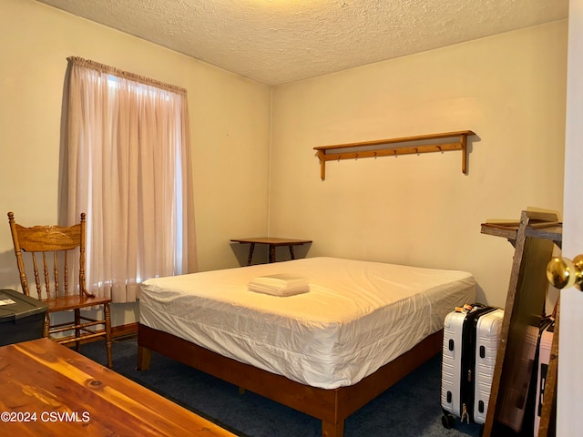 bedroom featuring dark colored carpet and a textured ceiling