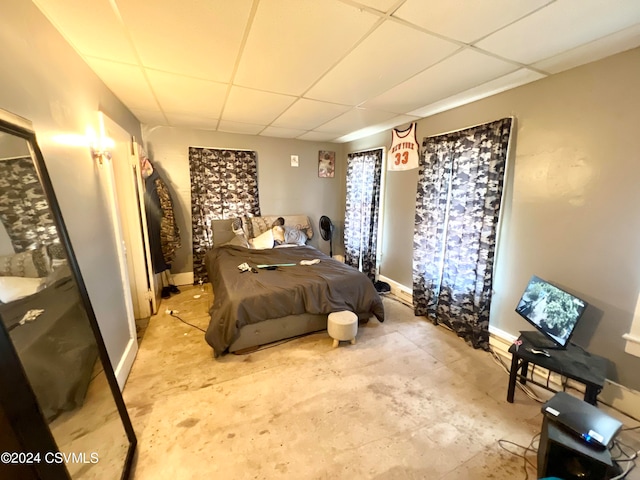 bedroom with a drop ceiling and concrete floors