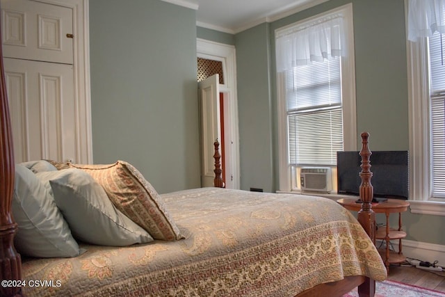 bedroom with ornamental molding, cooling unit, and wood-type flooring