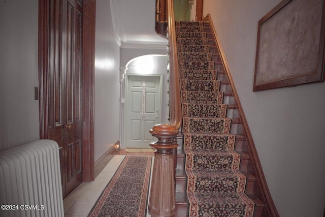 stairs featuring radiator, ornamental molding, and tile patterned flooring