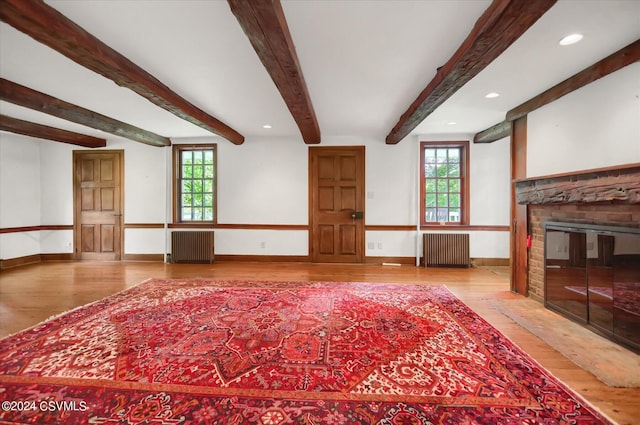 unfurnished living room with radiator, a wealth of natural light, and light hardwood / wood-style floors