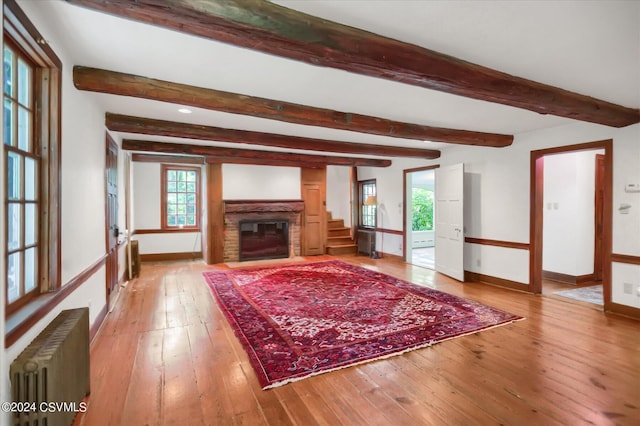 unfurnished living room with radiator, beamed ceiling, and hardwood / wood-style flooring