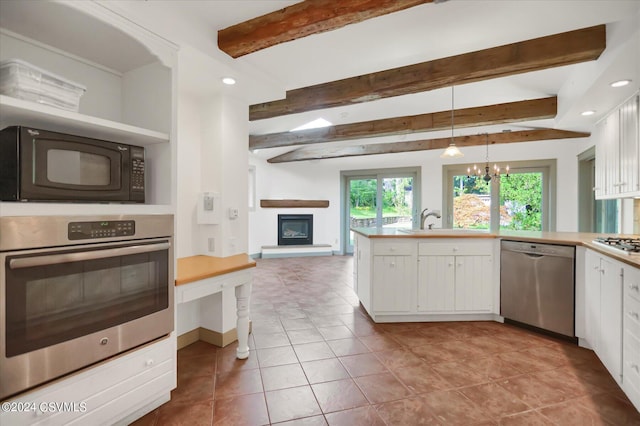 kitchen with stainless steel appliances, beam ceiling, white cabinets, and hanging light fixtures