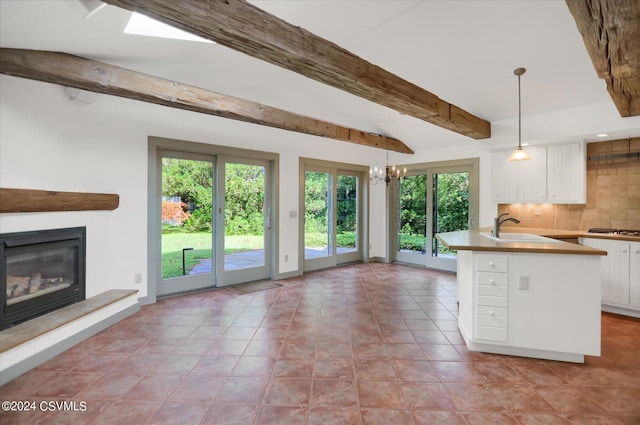 kitchen with white cabinets, decorative light fixtures, decorative backsplash, gas stovetop, and beam ceiling