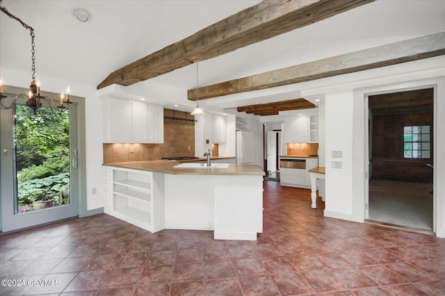 kitchen with hanging light fixtures, kitchen peninsula, tasteful backsplash, and white cabinetry