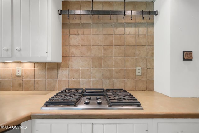 kitchen with stainless steel gas stovetop, white cabinets, and tasteful backsplash