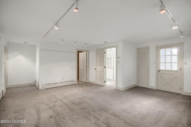 empty room with light carpet, a baseboard heating unit, and rail lighting