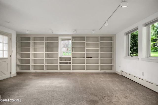 spare room featuring built in shelves, a baseboard heating unit, carpet, and track lighting