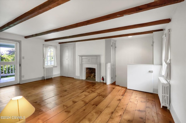 unfurnished living room featuring radiator, beam ceiling, and hardwood / wood-style flooring