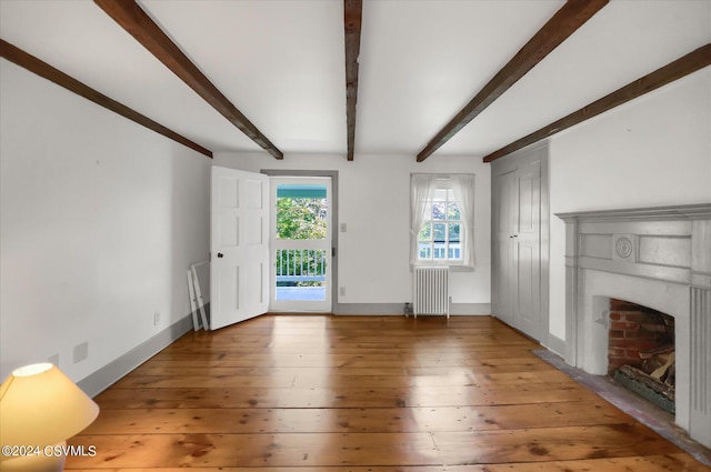 unfurnished living room with hardwood / wood-style flooring, radiator heating unit, beam ceiling, and a fireplace