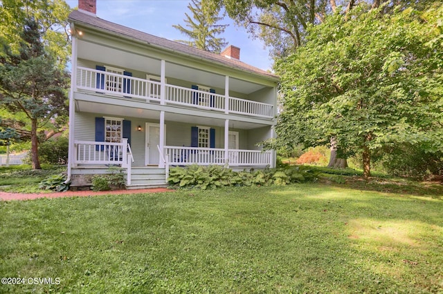 view of front of property with a front lawn, covered porch, and a balcony