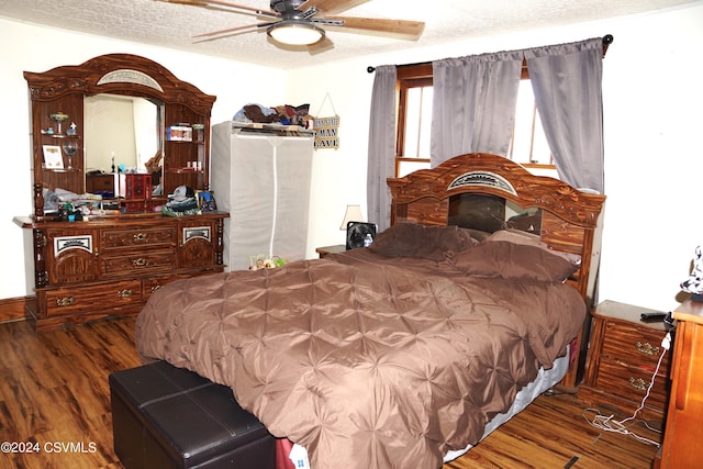 bedroom with a textured ceiling, ceiling fan, and dark wood-type flooring