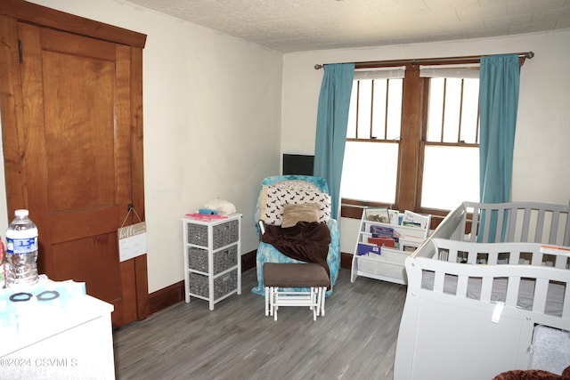 bedroom featuring wood-type flooring and a crib