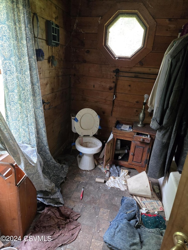 bathroom with toilet and wood walls